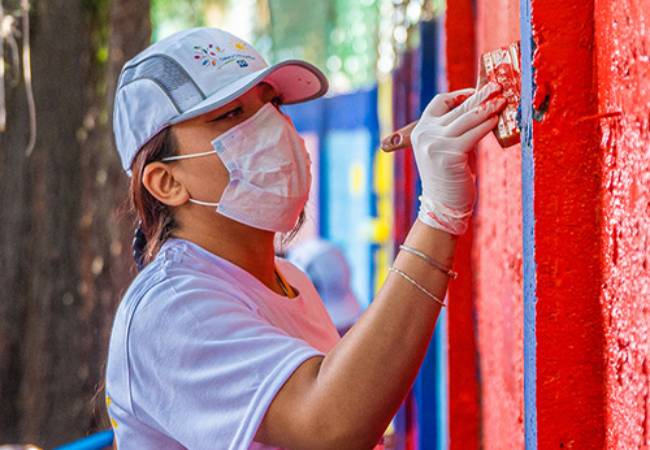 Woman painting a wall red in Mexico City, Mexico 