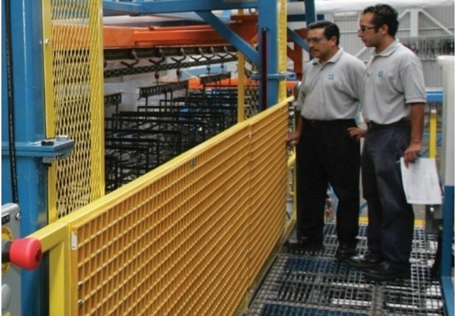 Two men over-looking a factory with yellow metal railings