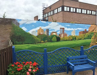 A blue bench next to a brick wall featuring a colorful city mural