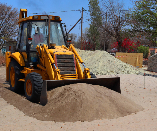 Yellow and black bulldozer in a building site pushing piles of sand