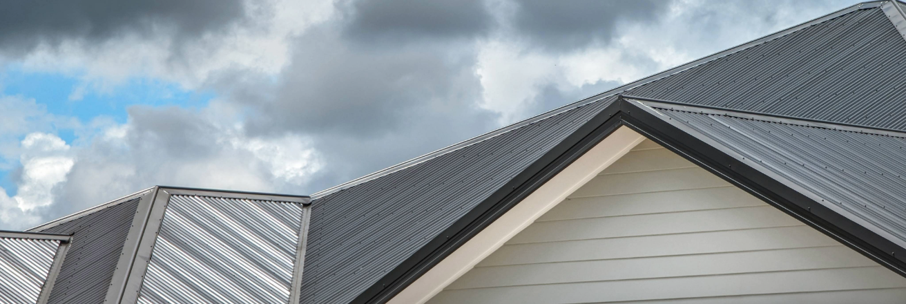 Grey roof sheets on a cream building against a cloudy sky