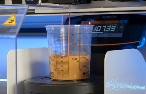 Paint being poured into measuring cup on scales