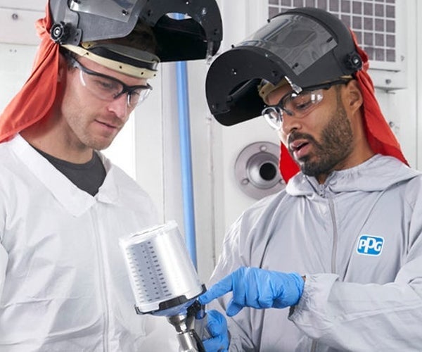 Two employees wearing PPE carrying out training with spray gun