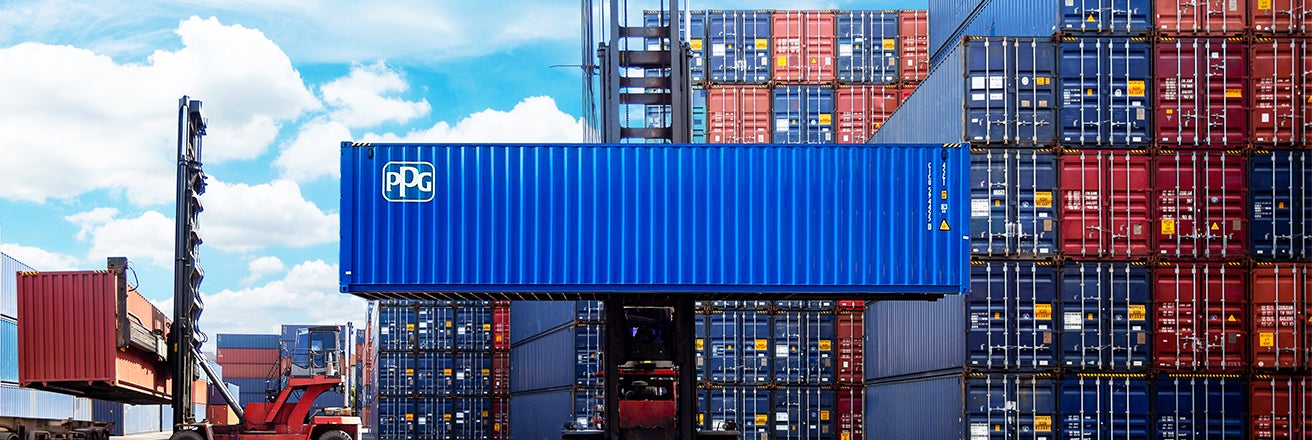 PPG shipping container sprayed in blue Envirocron powder. Lifted from the ground against a background shipping container park.