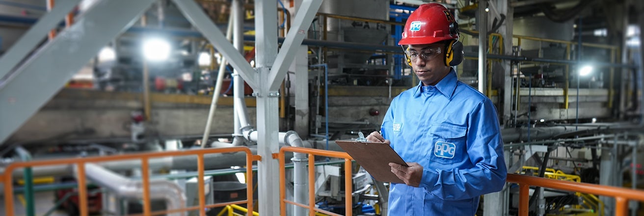 PPG employee wearing PPE inspecting manufacturing plant