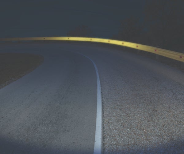 Road at night with barrier reflecting from headlights