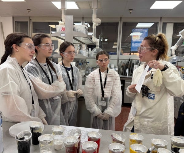 A group of women wearing white lab coats and goggles