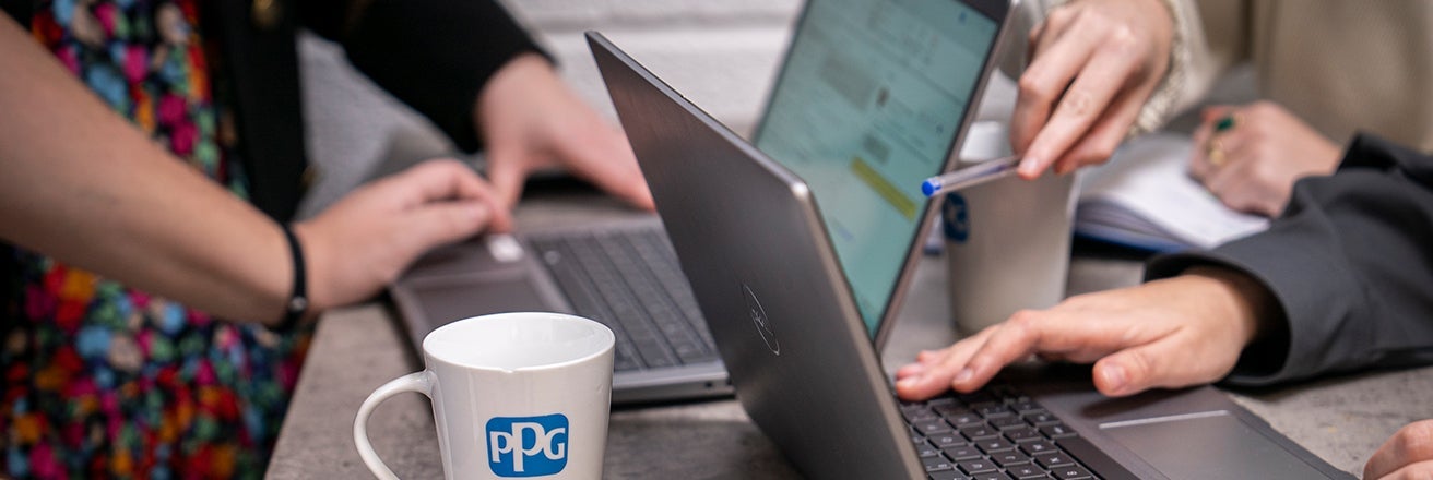 Closeup of laptops on a desk as employees discuss cyber security at PPG