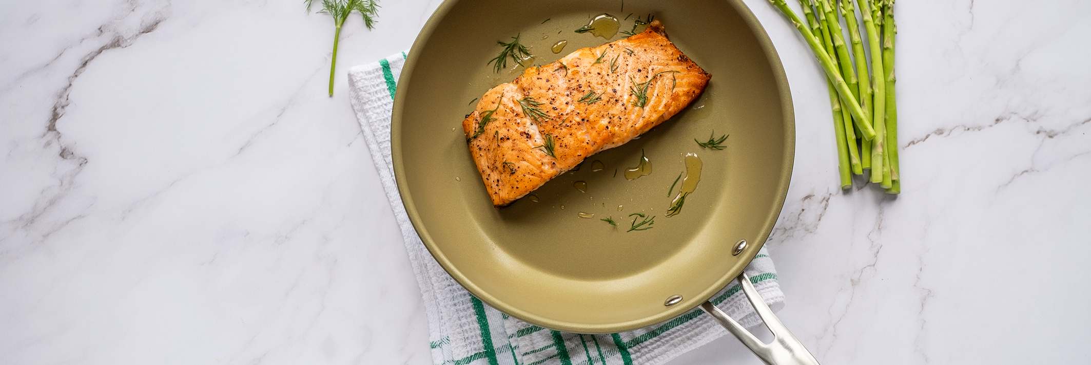 Eterna coated pan on a white kitchen surface with salmon and asparagus