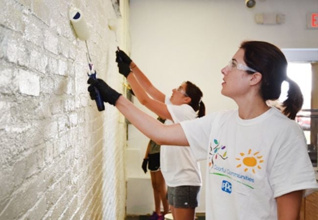 Woman painting brick interior wall with roller