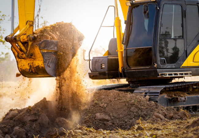 Yellow construction equipment moving dirt with digger