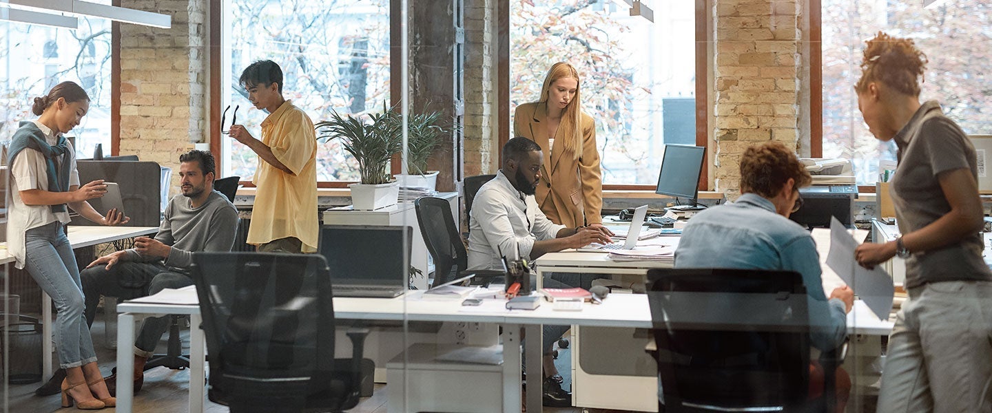 Group of men and women in an office environment discussing projects