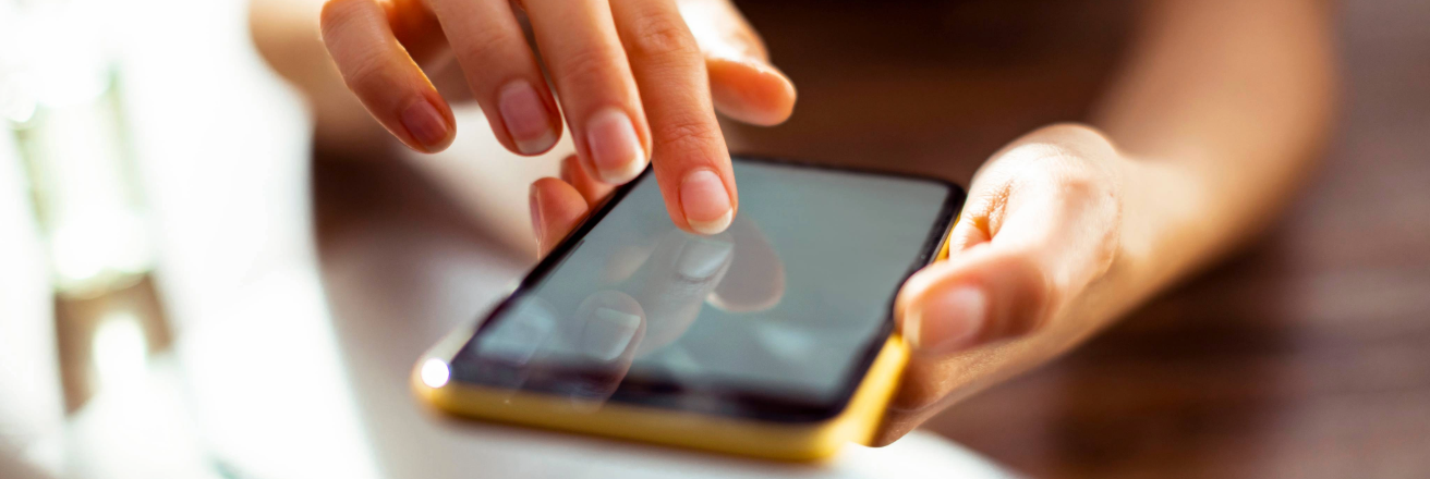 Lady with manicured nails holding a black mobile phone with a yellow case