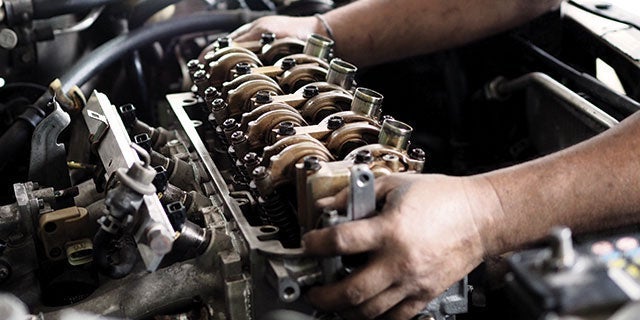 Close-up of a mechanic's hands working on a car's engine, showcasing intricate details of the engine components