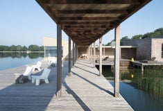 Een houten loopbrug met een dek en stoelen aan het water