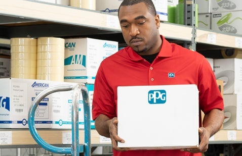 PPG employee carrying box in warehouse