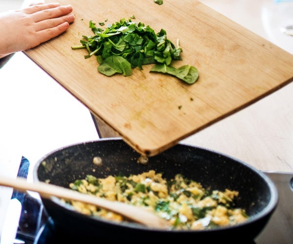 Man with young girl cooking in the kitchen with chopping board and cut greens 