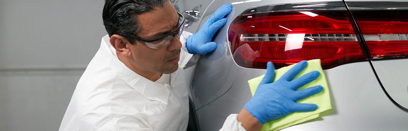 Technician wearing PPE polishing car panel