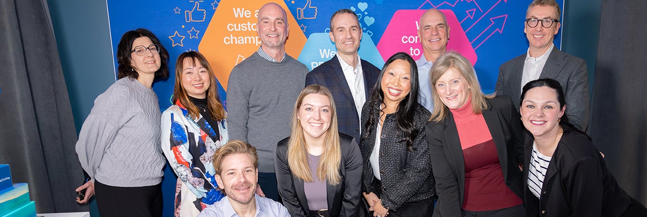 Group of PPG employees alongside Tim Knavish in front of brightly colored PPG banner