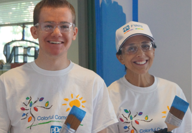 two volunteers painting a wall blue