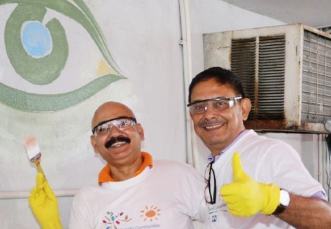 two volunteers painting wall in Kolkata, India 