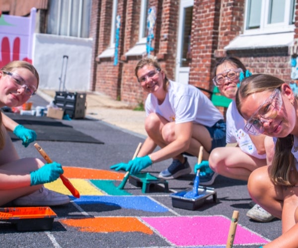 A group of women painting on a sidewalk