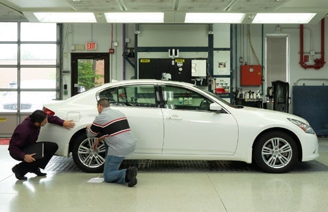 Workers examining car bodywork