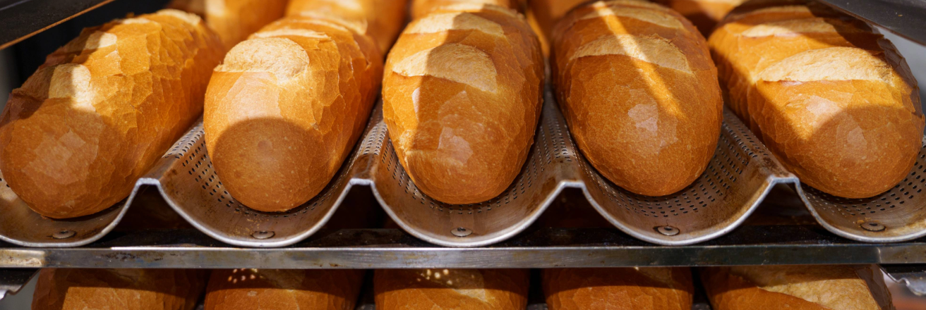 Line of baked baguettes on silver perforated tray