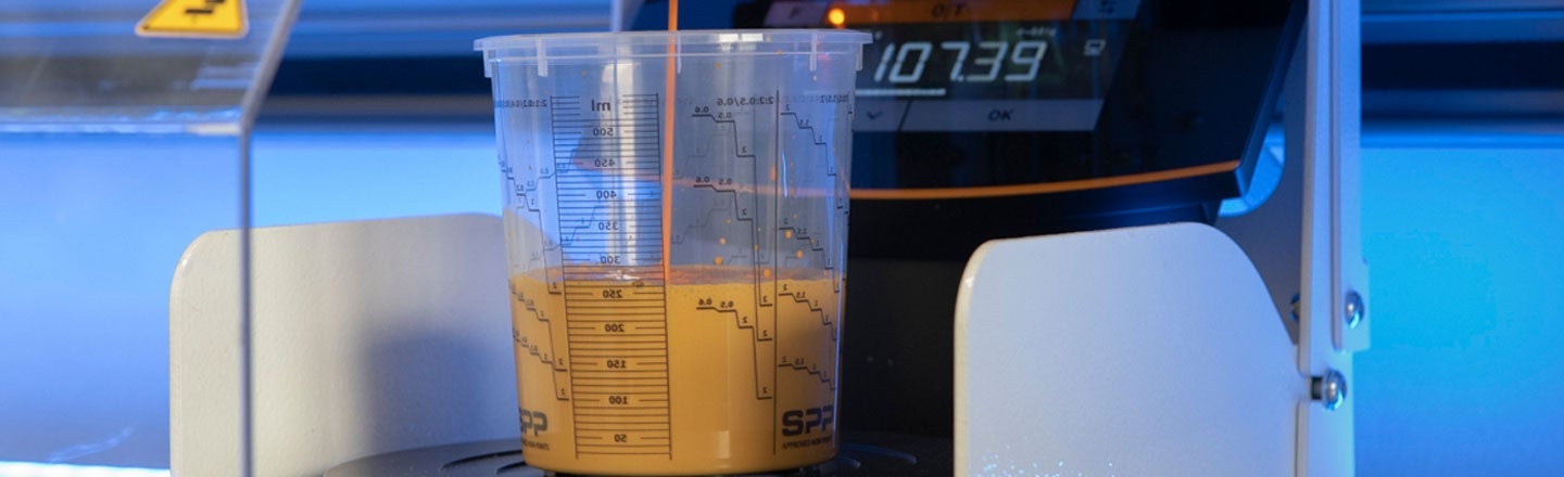 Paint being poured into measuring cup on scales