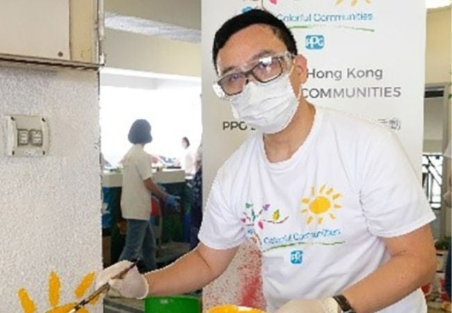 colorful communities volunteer painting sun mural on wall in Hong Kong, China