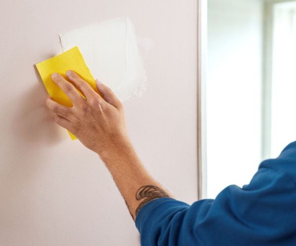 Hand som slipar en vägg