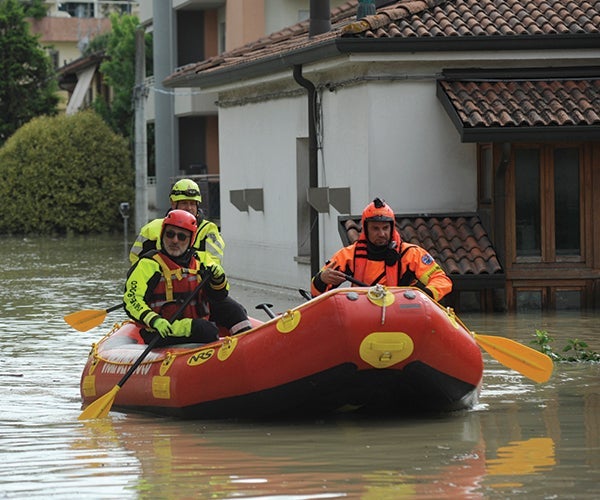 Rescue workers rowing boat in flooded area