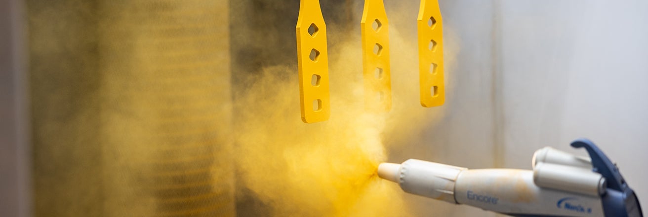 Spraying PPG sustainable yellow coating onto parts in a spray booth