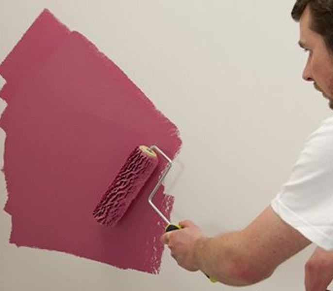 A man painting a wall with a paint roller