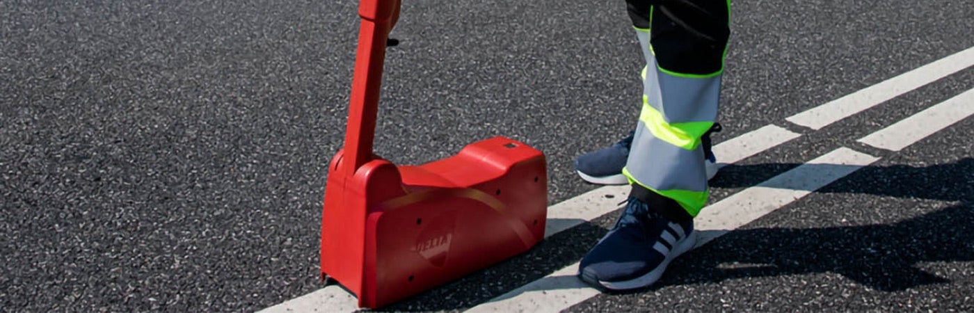 A worker using a machine to lay down road markings. ENNIS-FLINT® by PPG Application Equipment and Testing Instruments