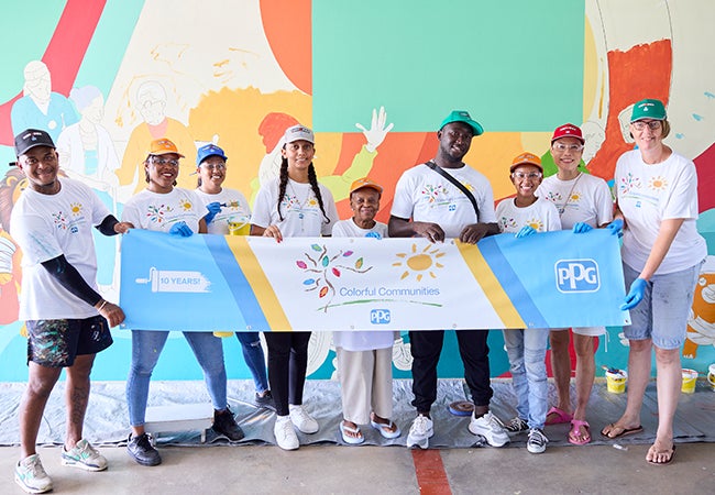 Group of volunteers at PPG's Colorful Communities next to colorful mural