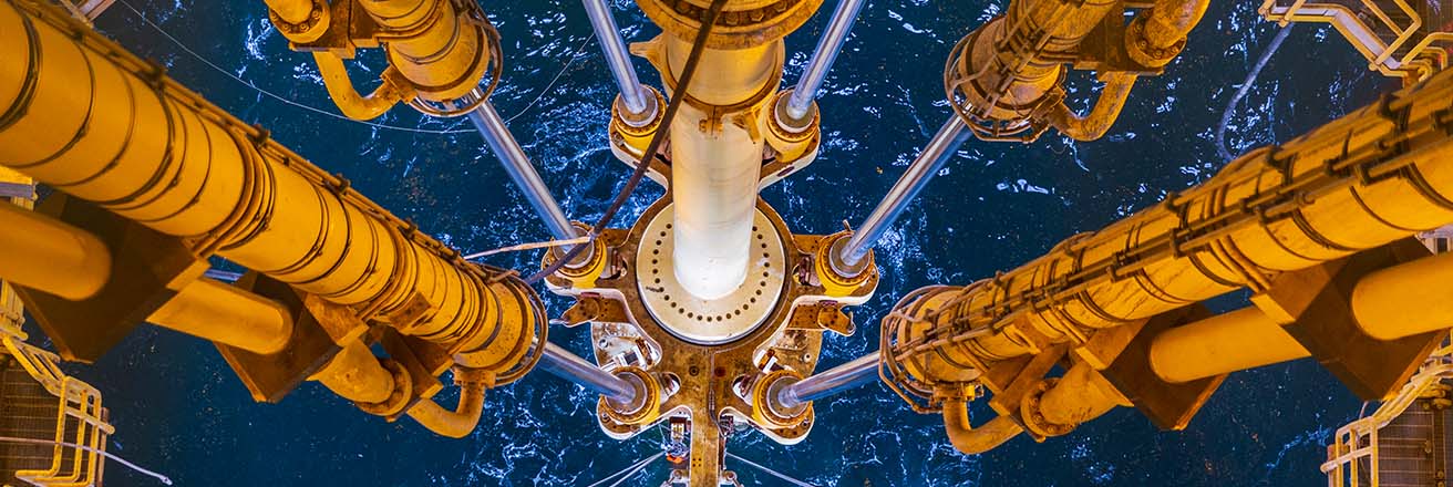 Image taken on an oil rig from a high structure looking down the yellow metal framework into blue sea