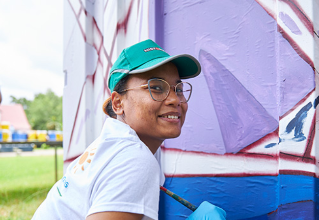 girl painting mural purple 