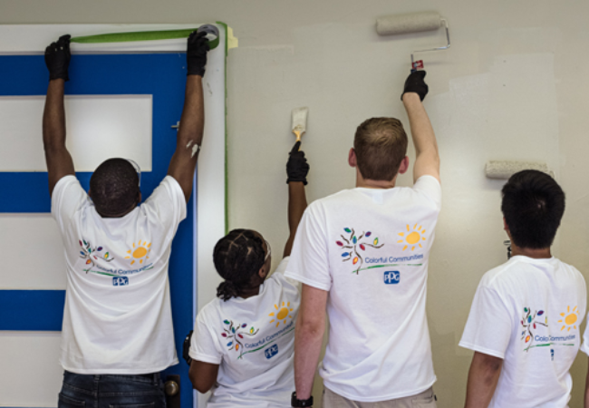 group of volunteers painting wall tan 