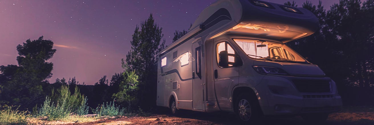 Motor home with internal lighting against a purple skyline