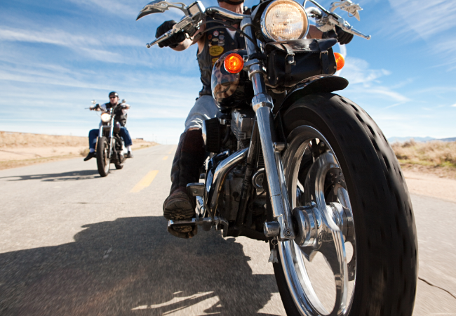 Two people riding motorcycles on desert road