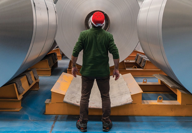 Male looking over rolls of coil metal