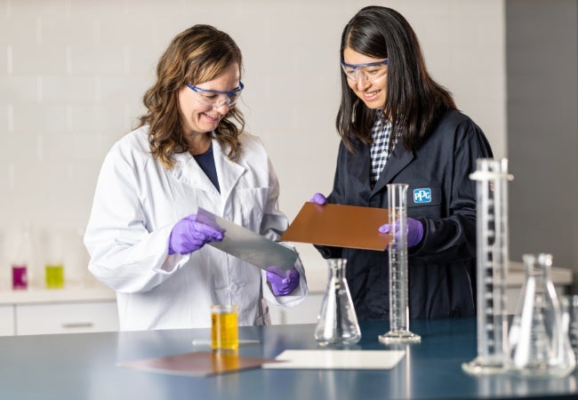 Two female chemists in a lab with measuring beakers and tubes of liquid