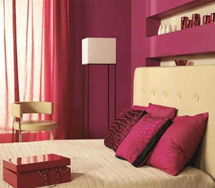 A bed with pink pillows and a white lamp