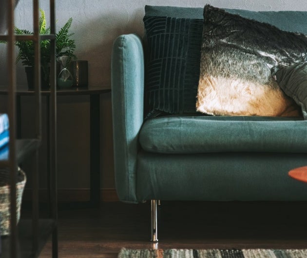 Zelený gauč s polštářem na něm