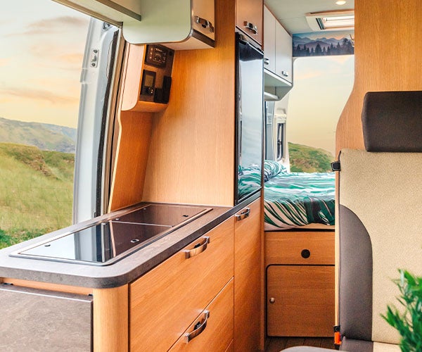 Internal view of a motor home with wooden kitchen fittings leading through into a sleeping area