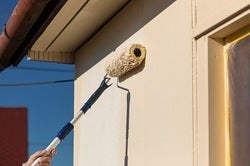 Osoba malující válečkem na zeď