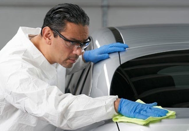 Man wearing PPE polishing car bodywork