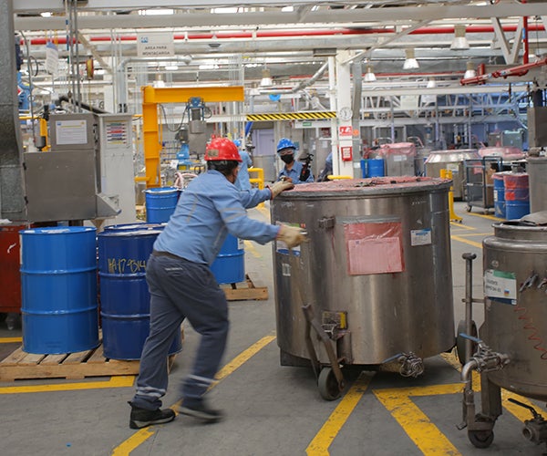 Workers moving large containers in factory