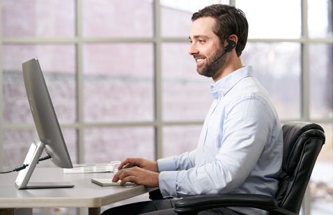 Man working at desk on computer wearing headset